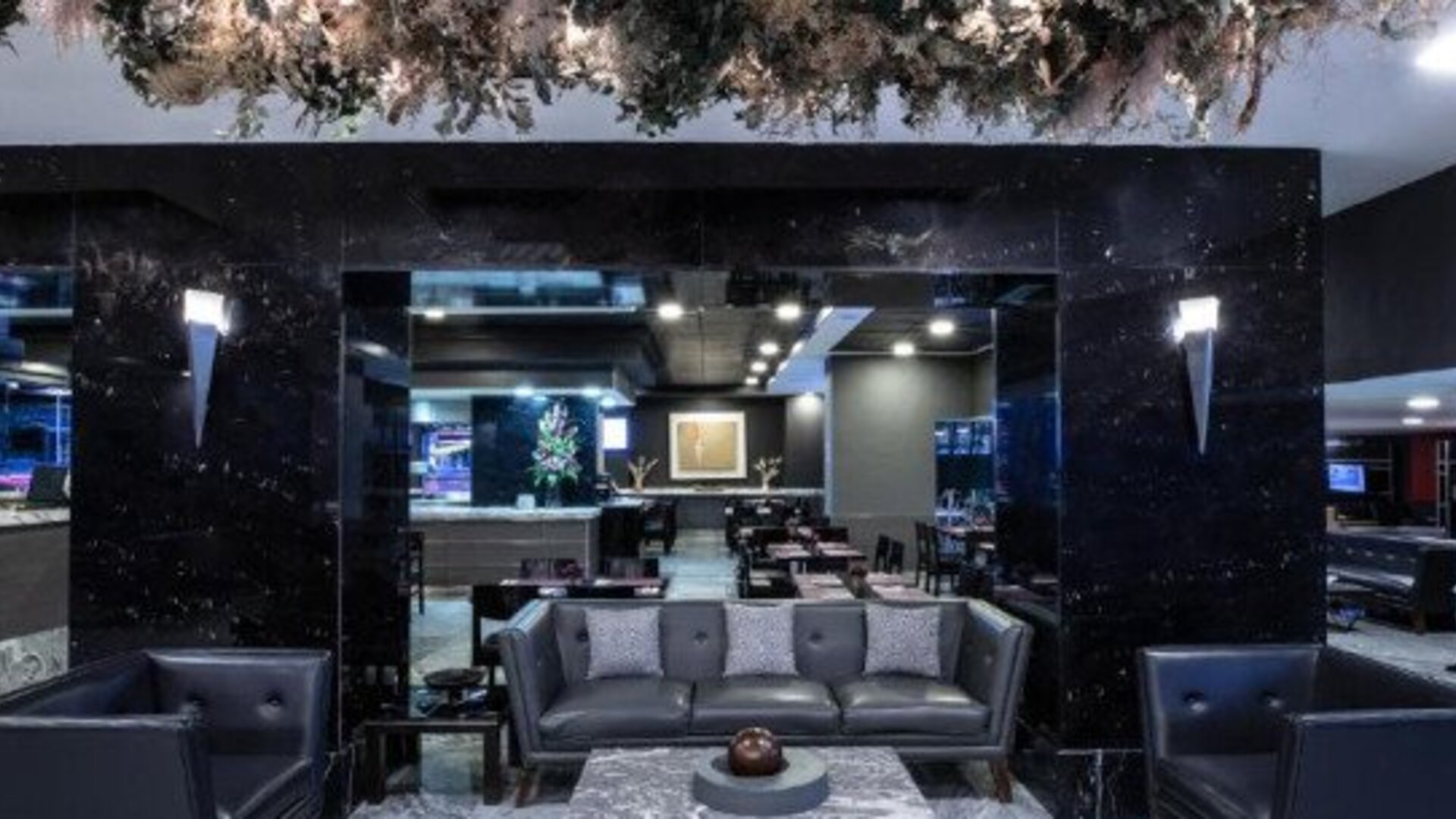 Contemporary hotel dining area with tables, chairs and large street-facing windows. LaiLa Hotel CDMX.