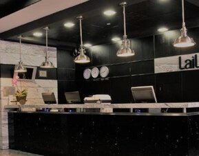 Modern reception desk featuring black and marble finishes with pendant lighting. LaiLa Hotel CDMX.