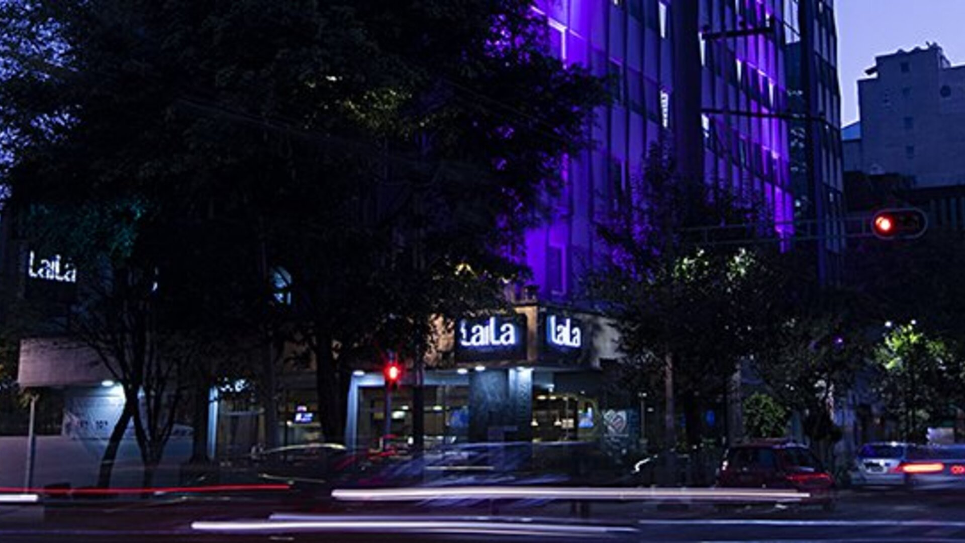 Evening exterior view of LaiLa Hotel CDMX with illuminated signage and purple accent lighting.