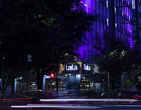 Evening exterior view of LaiLa Hotel CDMX with illuminated signage and purple accent lighting.