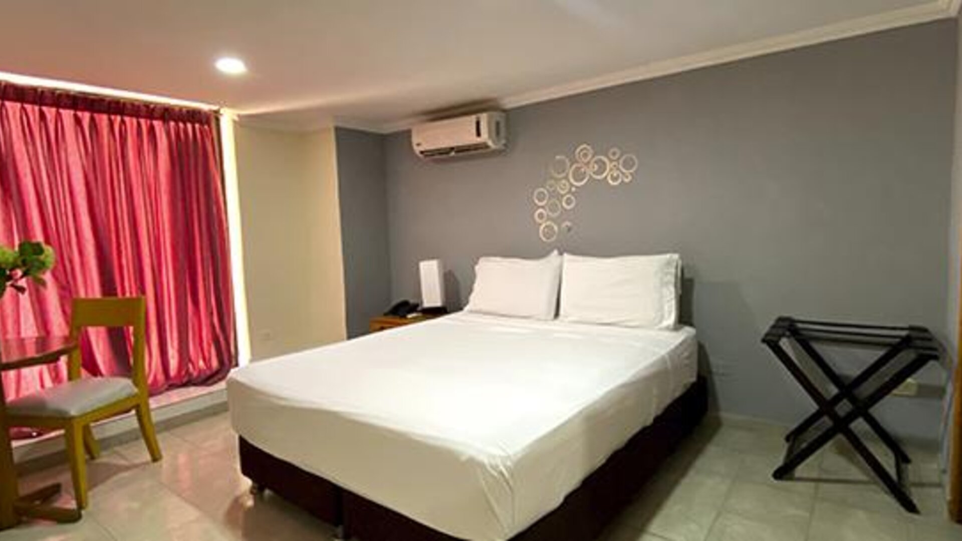 Guest room with double bed, dining table, luggage rack and air conditioning at Hotel Puerta de Oro.