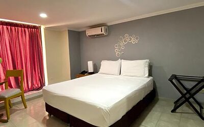 Guest room with double bed, dining table, luggage rack and air conditioning at Hotel Puerta de Oro.