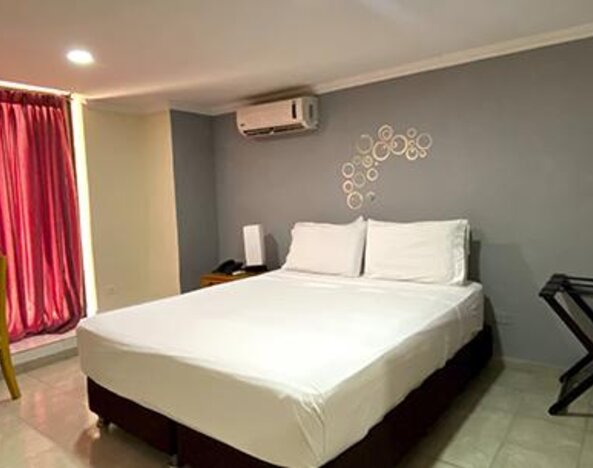 Guest room with double bed, dining table, luggage rack and air conditioning at Hotel Puerta de Oro.
