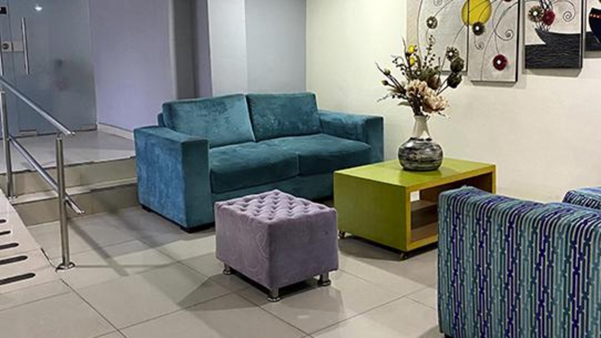 Modern hotel lobby with teal sofa, patterned seating, coffee table and artwork at Hotel Puerta de Oro.