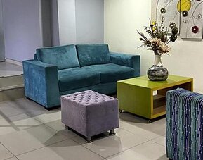 Modern hotel lobby with teal sofa, patterned seating, coffee table and artwork at Hotel Puerta de Oro.