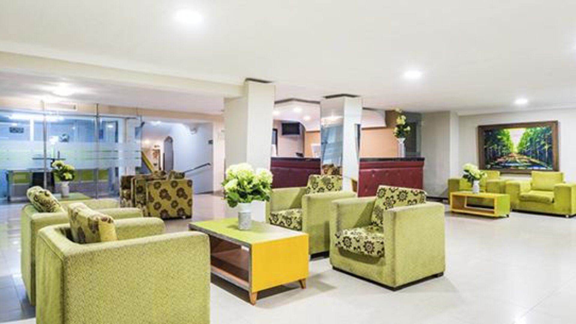 Hotel lobby with green armchairs, sofas, coffee tables and floral arrangements at Hotel Puerta de Oro.