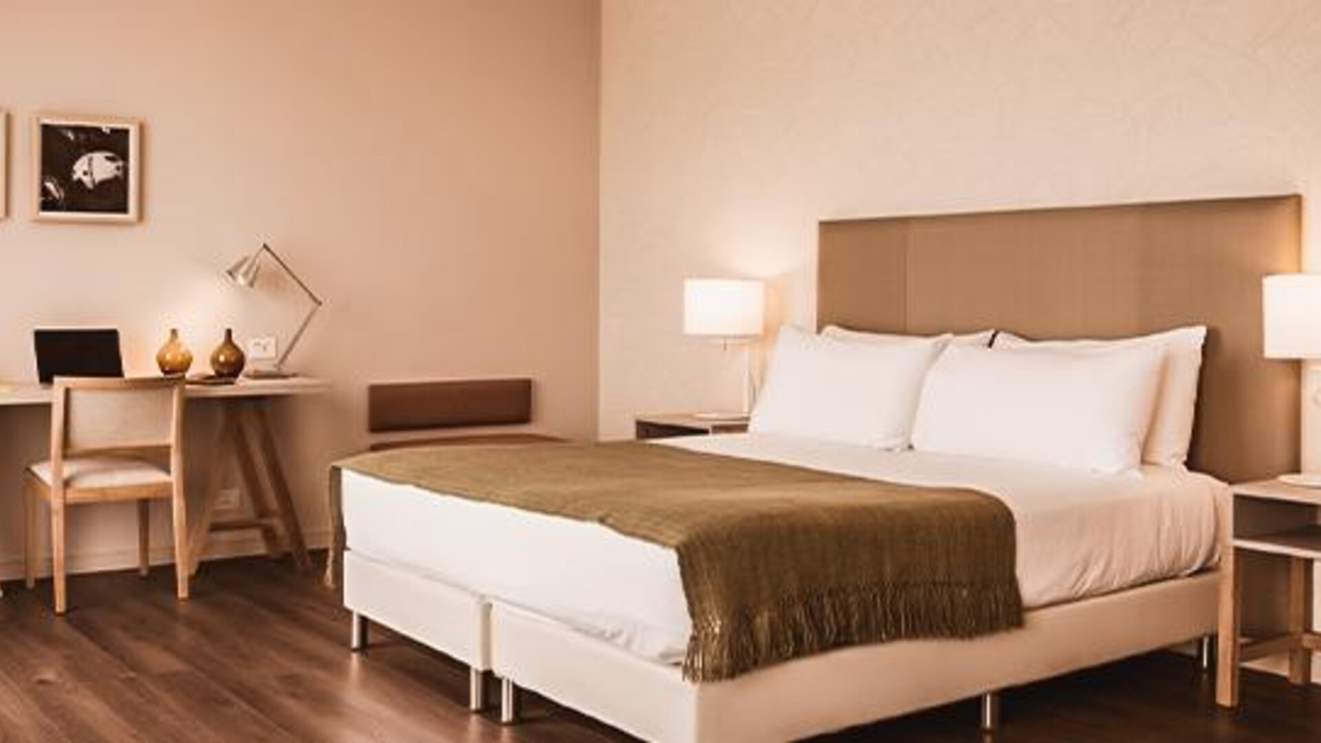Guest room with a large bed, desk, bedside tables, lamps, and framed artwork at Dazzler by Wyndham Polo.