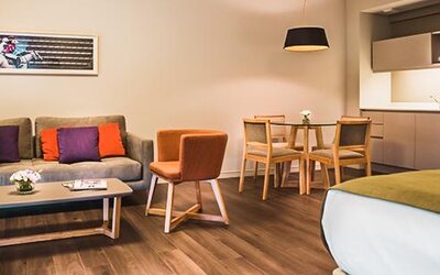 Guest room with a sofa, dining table, kitchenette, and bed in an open-plan layout at Dazzler by Wyndham Polo.