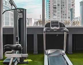 Fitness center with cardio and strength equipment, artificial grass flooring, and city views at Dazzler by Wyndham Polo.
