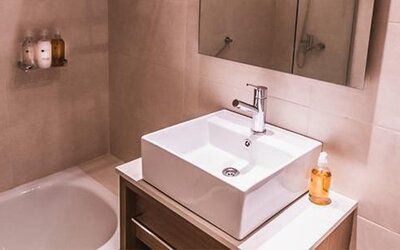 Modern bathroom with a white vessel sink, bathtub, wall mirror, and toiletries at Dazzler by Wyndham Polo.