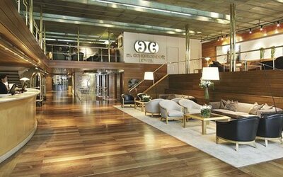 Spacious hotel lobby with a curved reception desk, wood flooring, lounge seating, and mezzanine at El Conquistador Hotel.