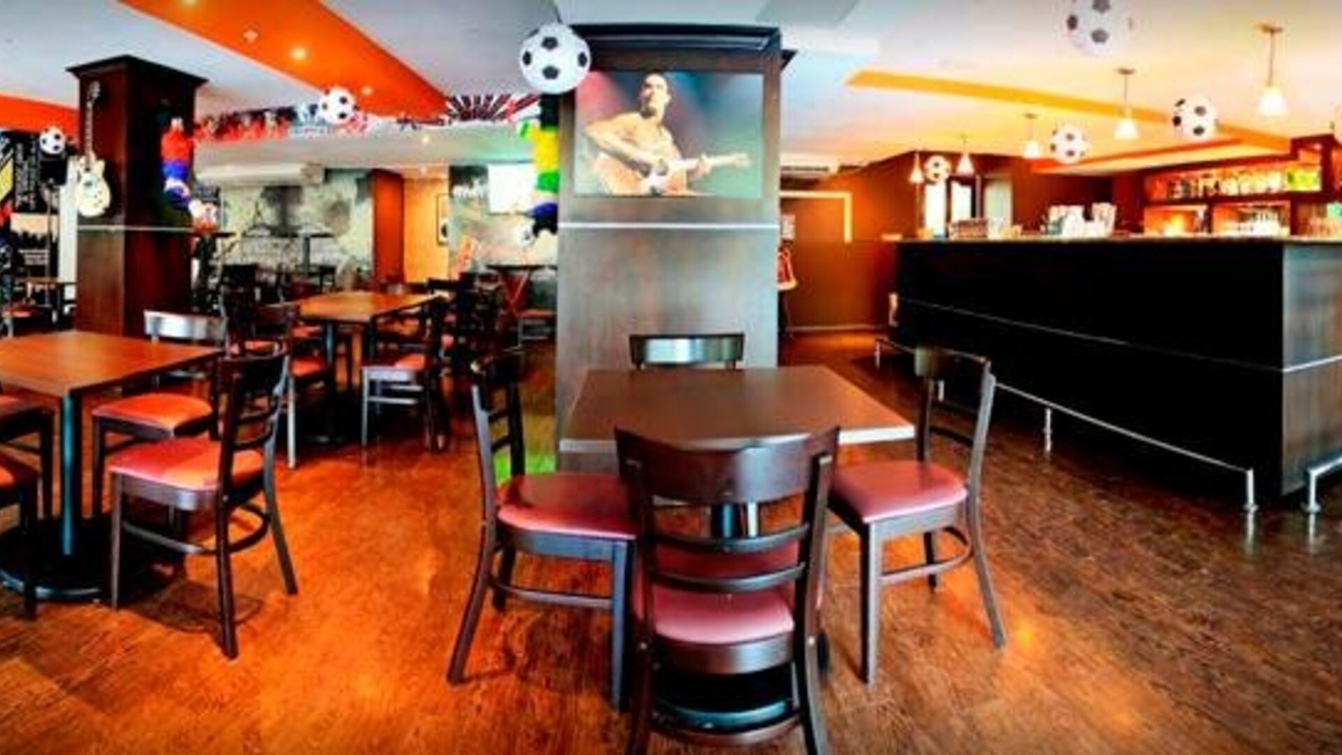 Restaurant and bar with wooden tables, chairs, a long counter, and soccer-themed hanging decorations at Hotel Grand International.