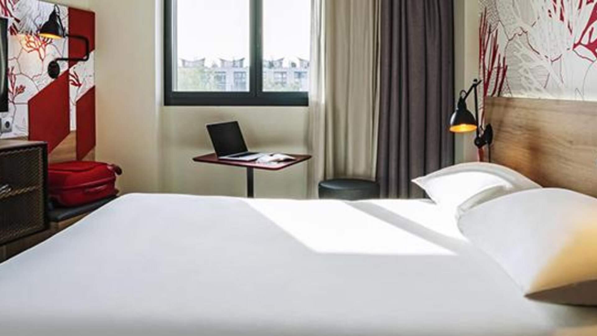 Guest room with a double bed, television, desk, chair, bedside reading lamps, and large window at Hotel ibis Styles Barcelona City Bogatell.