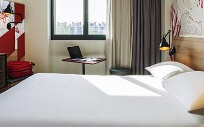 Guest room with a double bed, television, desk, chair, bedside reading lamps, and large window at Hotel ibis Styles Barcelona City Bogatell.