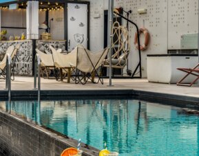 Rooftop terrace overlooking the city with a swimming pool, lounge chairs, canopy, and outdoor bar at Hotel ibis Styles Barcelona City Bogatell.