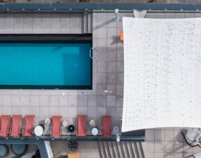 Aerial view of the rooftop pool, surrounding lounge chairs, canopy, and terrace seating at Hotel ibis Styles Barcelona City Bogatell.