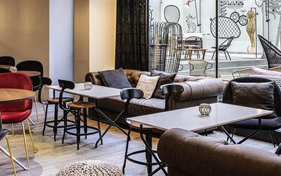 Indoor lounge with sofas, armchairs, round tables, pendant lighting, and views of the rooftop terrace at Hotel ibis Styles Barcelona City Bogatell.