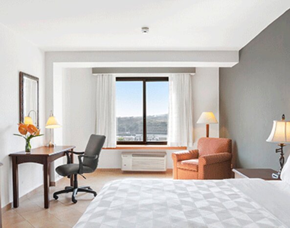 Guest room with a king bed, desk, office chair, armchair, television and large window overlooking the landscape at Holiday Inn Panama Canal.