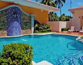 Outdoor swimming pool surrounded by lounge chairs, tropical landscaping and a tiled waterfall feature at Holiday Inn Panama Canal.