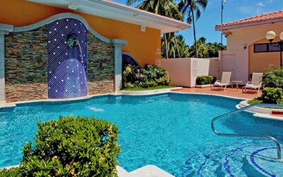 Outdoor swimming pool surrounded by lounge chairs, tropical landscaping and a tiled waterfall feature at Holiday Inn Panama Canal.