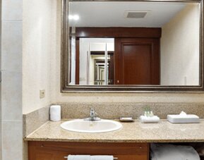 Hotel bathroom with a granite vanity, sink, large mirror and tiled shower at Holiday Inn Panama Canal.