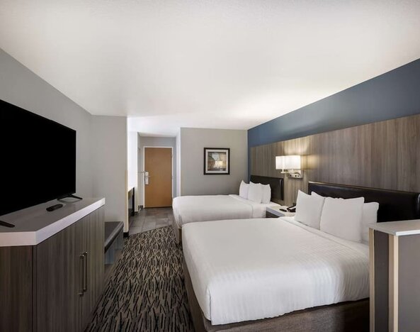 Guest room with two beds, a television, dresser, desk, and seating area at Best Western Plus Mountain View Auburn Inn.