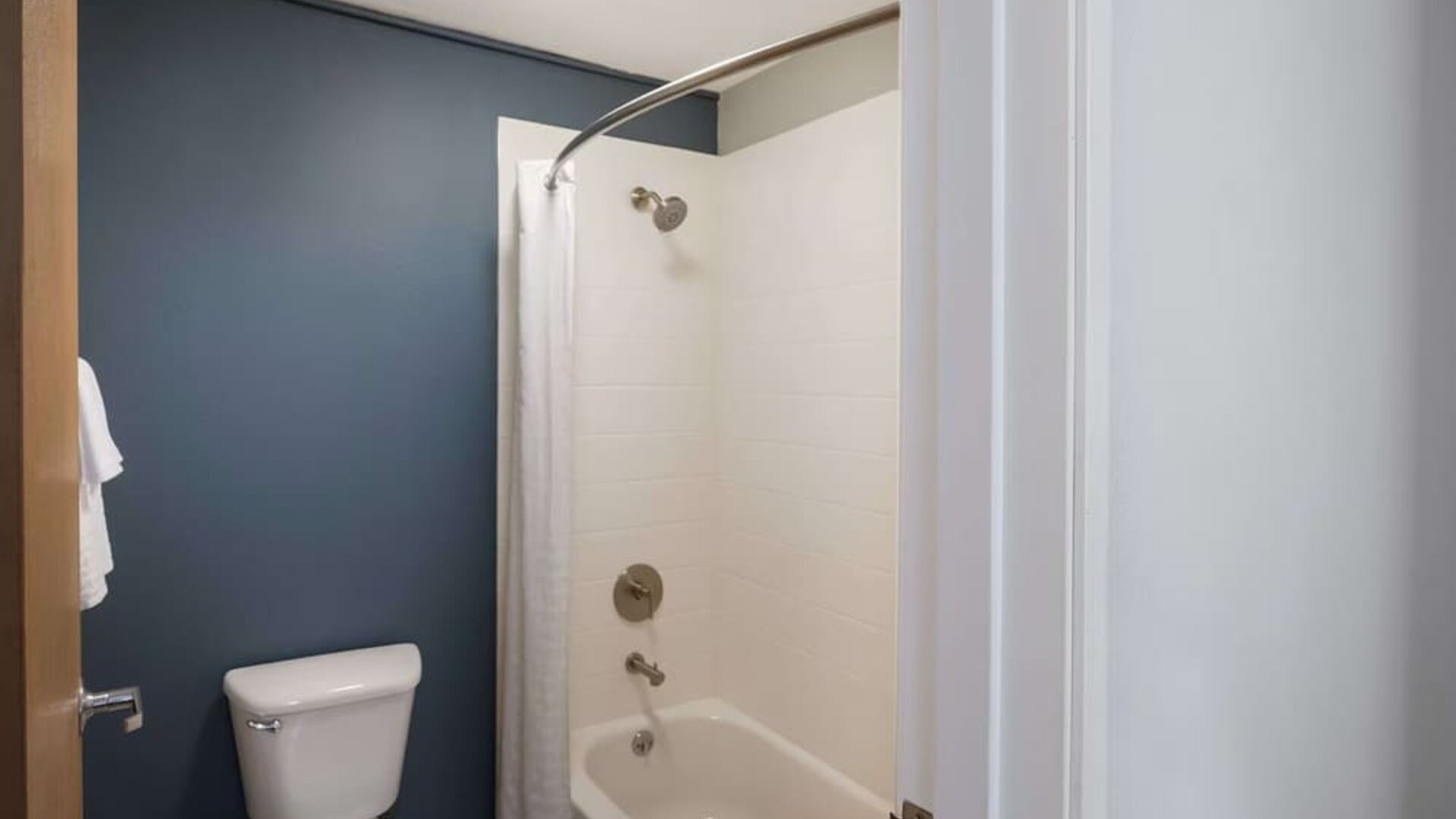 Bathroom with a bathtub, shower, toilet, and dark blue accent wall at Best Western Plus Mountain View Auburn Inn.