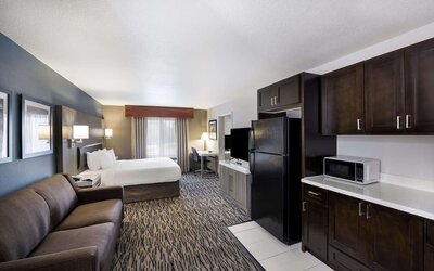 Spacious suite with a king bed, sofa, kitchenette, refrigerator, microwave, and desk at Best Western Plus Mountain View Auburn Inn.