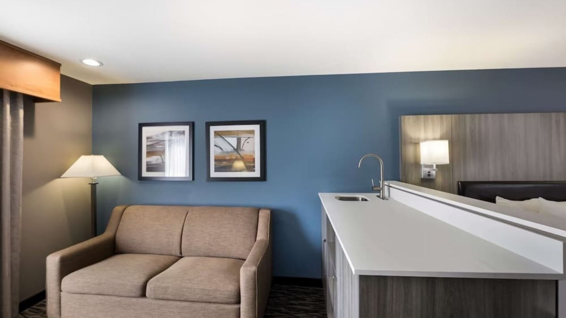 Suite seating area with a sofa, counter, sink, and lamp at Best Western Plus Mountain View Auburn Inn.