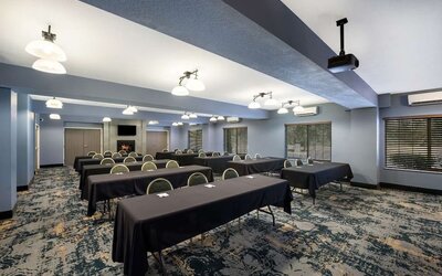 Conference room with rows of tables, chairs, and a presentation screen at Best Western Plus Mountain View Auburn Inn.