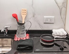 Kitchenette with sink, cookware, utensils and electric stovetop at Ramada by Wyndham Buenos Aires Centro.