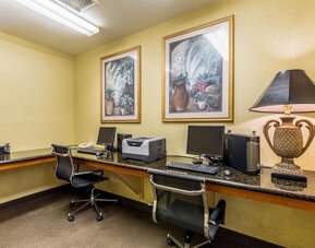 Business center with two computer workstations, monitors, keyboards, office chairs, printer, and decorative artwork at Sleep Inn & Suites Stafford - Sugar Land.