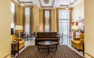 Hotel lobby with a breakfast and coffee station, round dining tables, chairs, sofas, reception area, and high ceilings at Sleep Inn & Suites Stafford - Sugar Land.