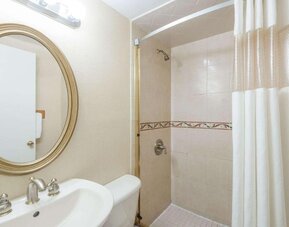 Bathroom with a glass-enclosed shower, white shower curtain, pedestal sink, oval wall mirror, and tiled shower walls at Howard Johnson Express Inn - Rocky Hill.