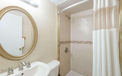 Bathroom with a glass-enclosed shower, white shower curtain, pedestal sink, oval wall mirror, and tiled shower walls at Howard Johnson Express Inn - Rocky Hill.