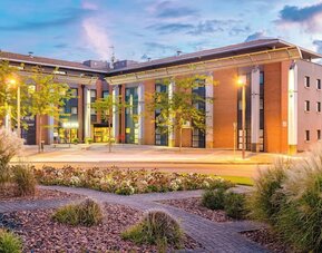 Exterior of Holiday Inn Toulouse Airport with landscaped gardens, brick and beige facade, and illuminated entrance.