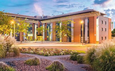 Exterior of Holiday Inn Toulouse Airport with landscaped gardens, brick and beige facade, and illuminated entrance.