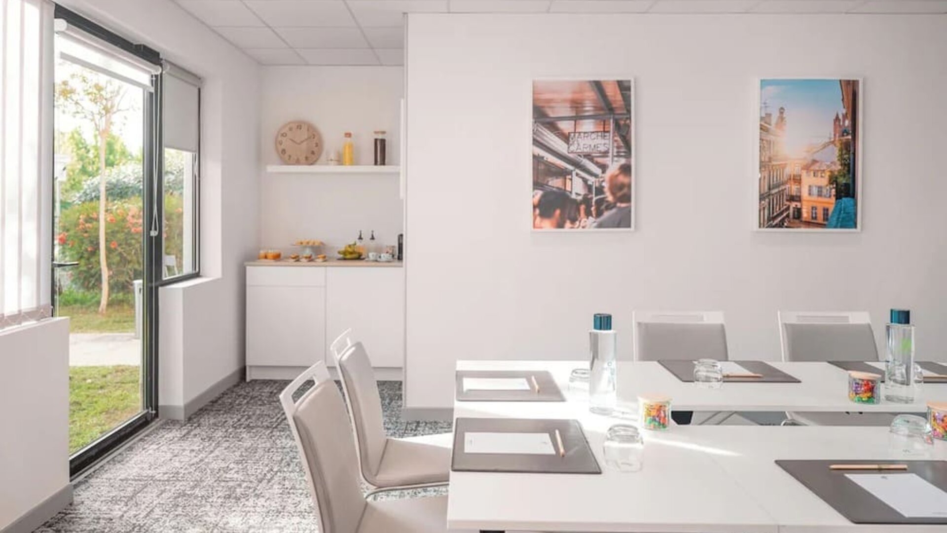 Meeting room with white tables and chairs, large windows, and a refreshment area at Holiday Inn Toulouse Airport.