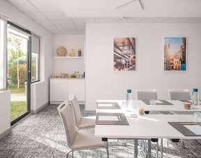 Meeting room with white tables and chairs, large windows, and a refreshment area at Holiday Inn Toulouse Airport.