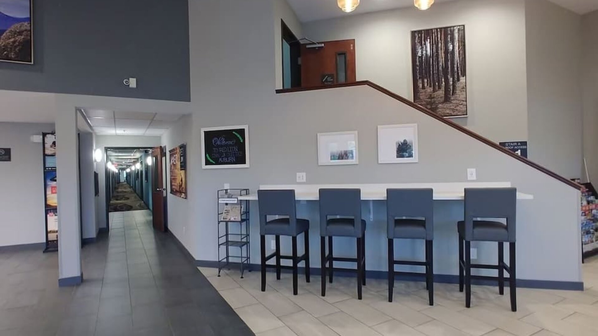 Hotel lobby seating area with upholstered chairs and sofas, large windows, coffee tables, and contemporary decor at Garner by IHG.