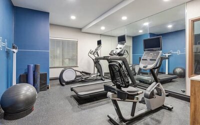 Hotel fitness center with treadmills, elliptical machines, stationary bike, exercise balls, and mirrored walls at Holiday Inn Express & Suites Granbury.