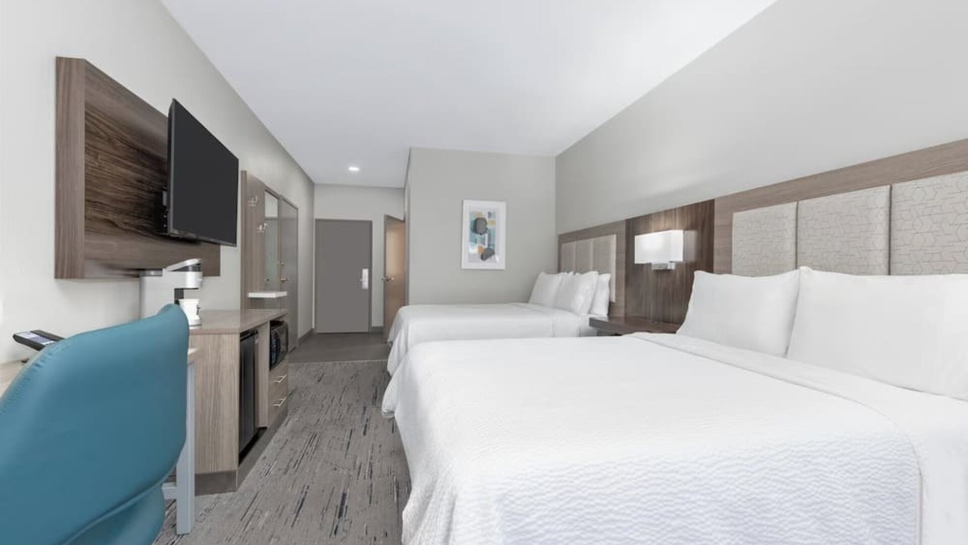 Guest room with two queen beds, white bedding, wood headboard, blue office chair, desk, dresser, and wall-mounted TV at Holiday Inn Express & Suites Granbury.