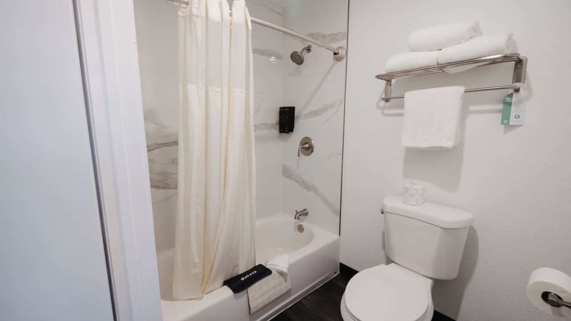 Guest room with two beds, white bedding, green accent wall, bedside lamps, and a window with natural light at Western Inn.