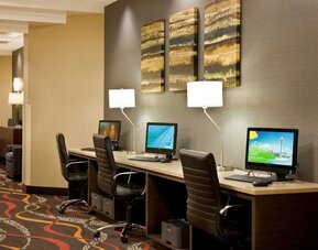 Business center featuring multiple computer workstations, office chairs, desk lamps, and wall art at Best Western Plus BWI Airport Arundel Mills.