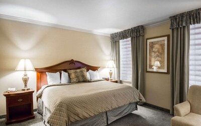 ing bedroom featuring a large wooden headboard, beige patterned bedding, decorative accent pillows, bedside tables with lamps, neutral walls, and a carpeted floor at Liberty Hotel Cleburne, an Ascend Hotel Collection Member.