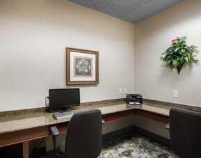 Business center with granite countertops, desktop computer, printer, office chairs, framed artwork, and decorative greenery at Liberty Hotel Cleburne, an Ascend Hotel Collection Member.