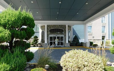 The hotel’s covered entrance is surrounded by landscaped gardens, trimmed shrubs and stone accents around the glass doors at Comfort Inn & Suites Glen Mills – Concordville.