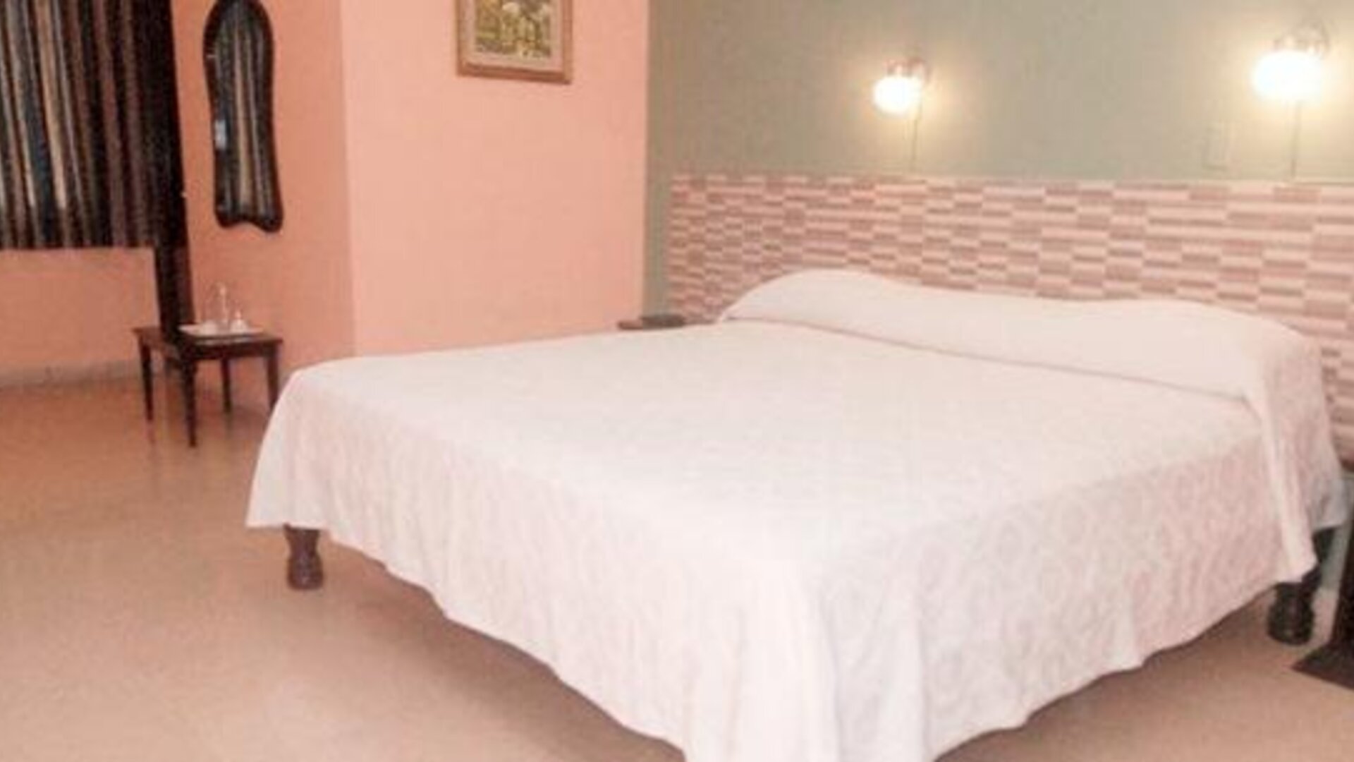 Double bed with white bedding, a geometric headboard and wall-mounted bedside lights at Caribe Panamá Hotel.
