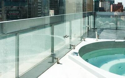 Outdoor whirlpool bath on a rooftop terrace with glass safety railings and city views at Hotel Block Suites.
