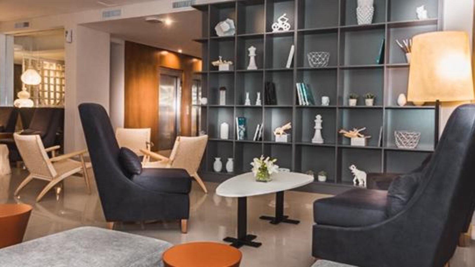Hotel lobby with armchairs, coffee tables, decorative shelving and contemporary lighting at Howard Johnson Plaza Buenos Aires.
